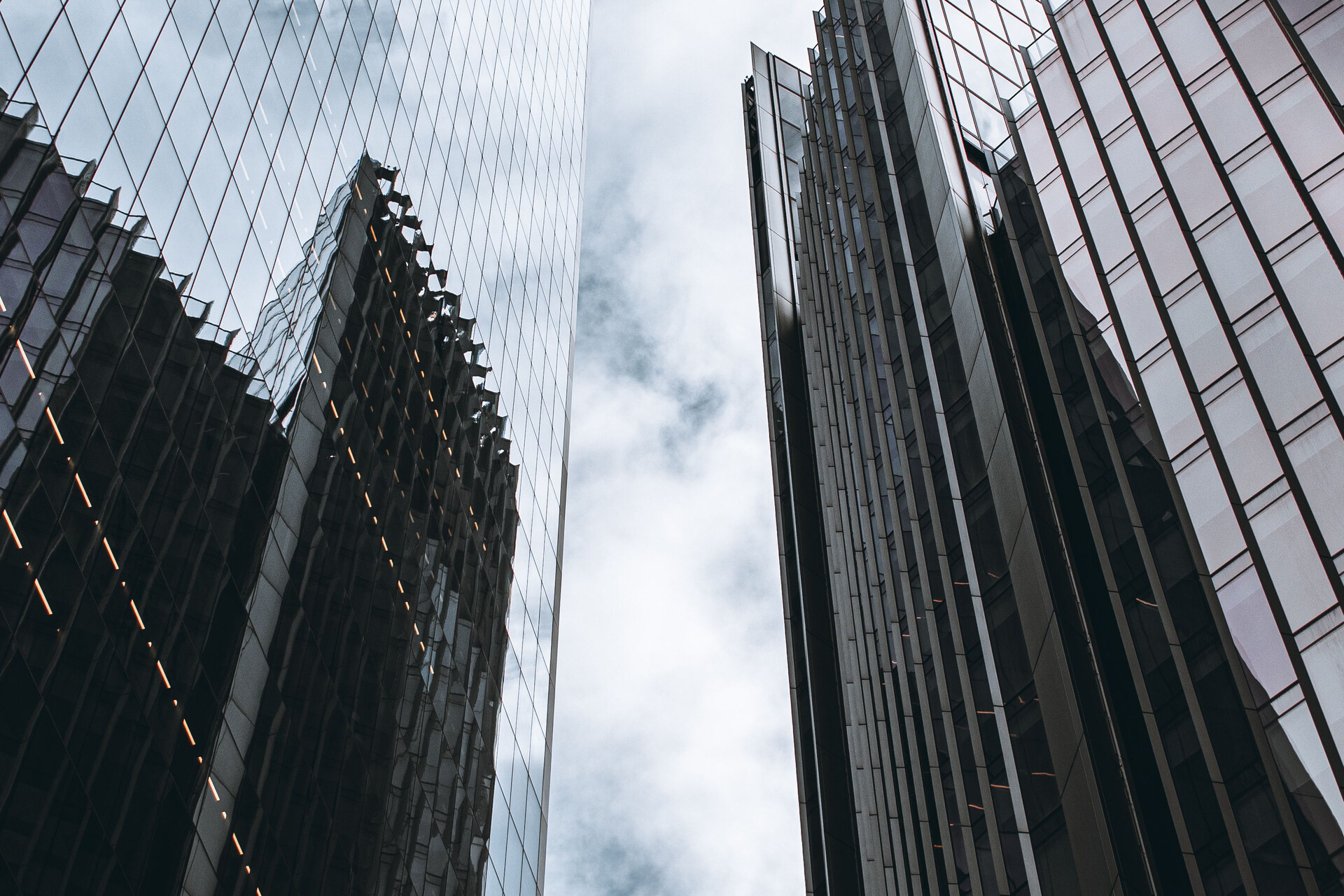 London skyscraper glass facades viewed from below, reflecting clouds