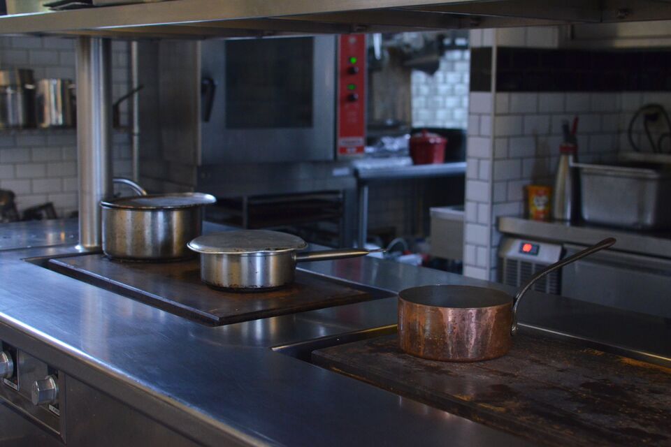 Cucina professionale con piani in acciaio inox e pentole di rame e acciaio