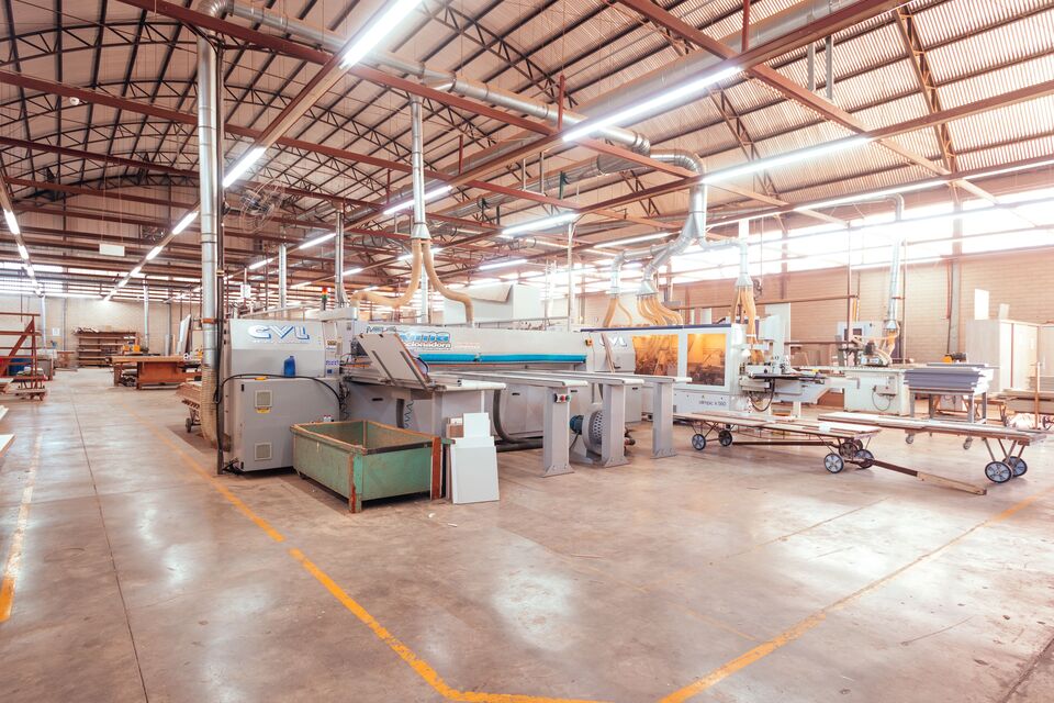 Ampio reparto di produzione industriale con linee di macchinari e capriate in acciaio
